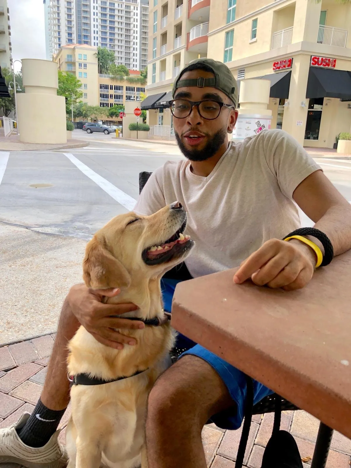 Owner at a street café with a calm yellow Labrador beside the table